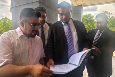 Muhammad Rafique menunjukkan dokumen kepada Chegubard (kiri) ketika di Kompleks Mahkamah Seremban.