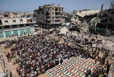 Penduduk Gaza menunaikan solat jenazah di tengah-tengah runtuhan struktur musnah dibedil di kawasan kejiranan al-Sabra di Bandar Gaza.