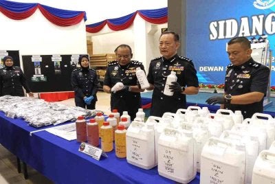 Chuan Huat (tengah) menunjukkan perisa vape yang dirampas daripada sindiket.