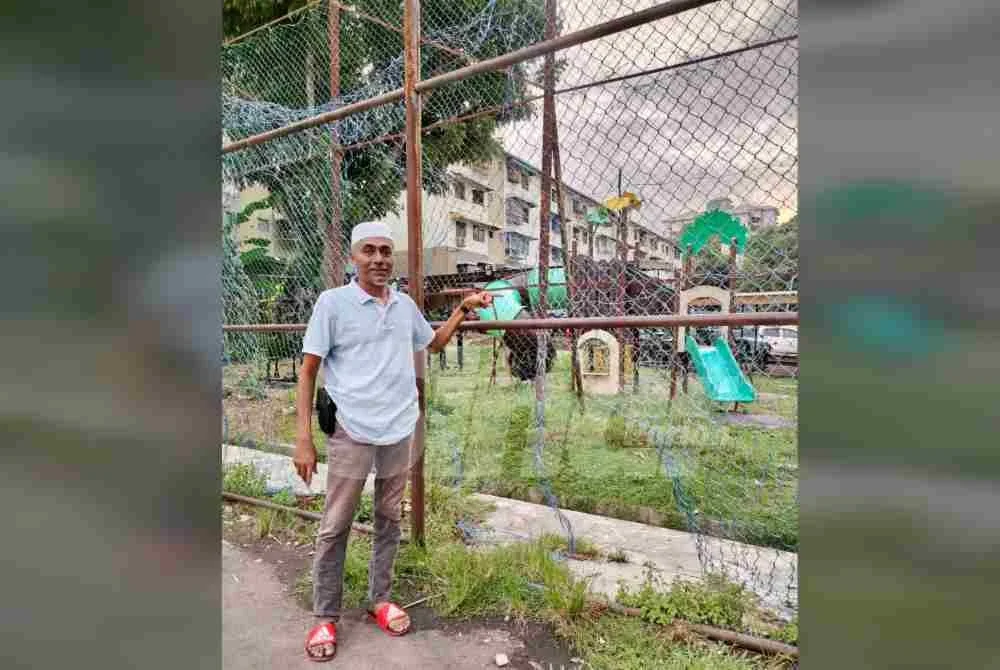 Mohd Farook menunjukkan keadaan pagar dawai gelanggang futsal di Flat Bukit Gedung yang mengalami kerosakan teruk dan memerlukan perhatian segera pihak berwajib.