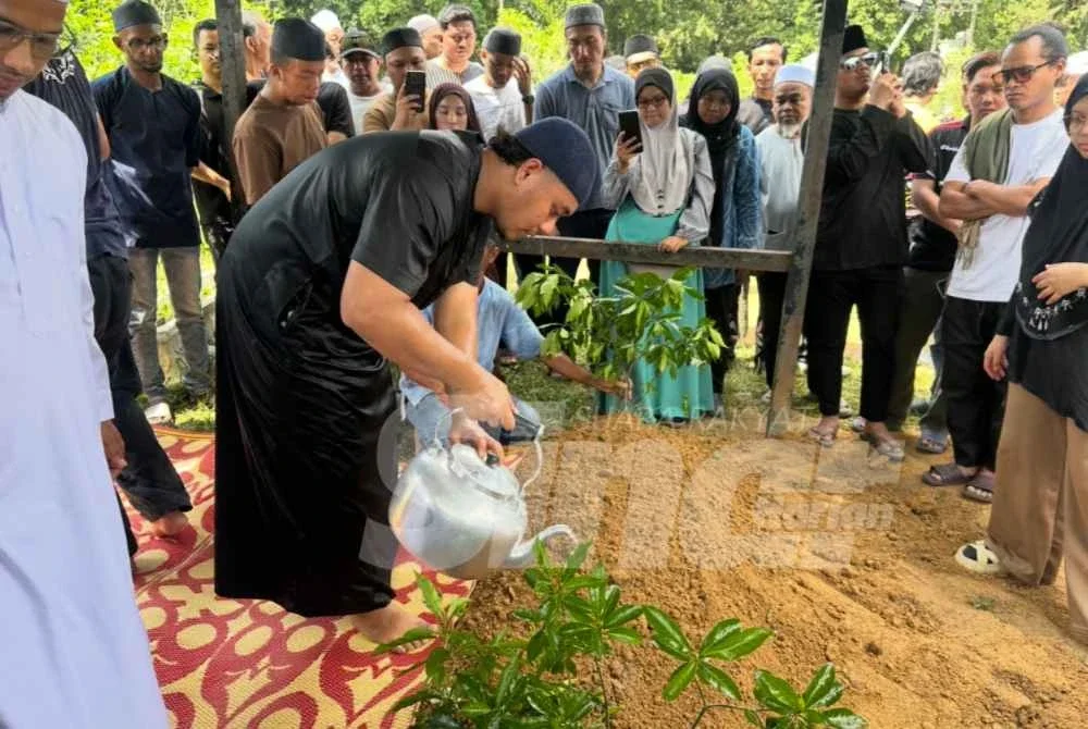 Ahmad Fakrul Alif (kiri) menyiram pusara ayahnya yang meninggal dunia akibat sakit jantung. Foto SINAR HARIAN/ADILA SHARINNI WAHID