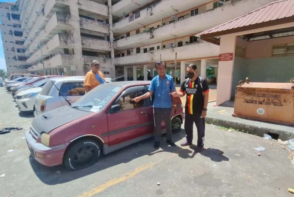 Mohamad (tengah) menunjukkan keadaan salah sebuah kereta terbiar di Pangsapuri Seri Perantau.