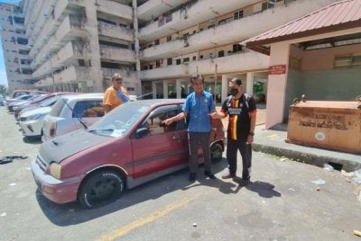 Mohamad (tengah) menunjukkan keadaan salah sebuah kereta terbiar di Pangsapuri Seri Perantau.