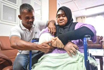 Abdul Wahid (kiri) melihat kecederaan pada tangan kanan isterinya yang patah selepas kenderaan mereka merempuh sekumpulan gajah liar ketika ditemui di rumahnya di Kampung Pasir Gajah. Foto Bernama