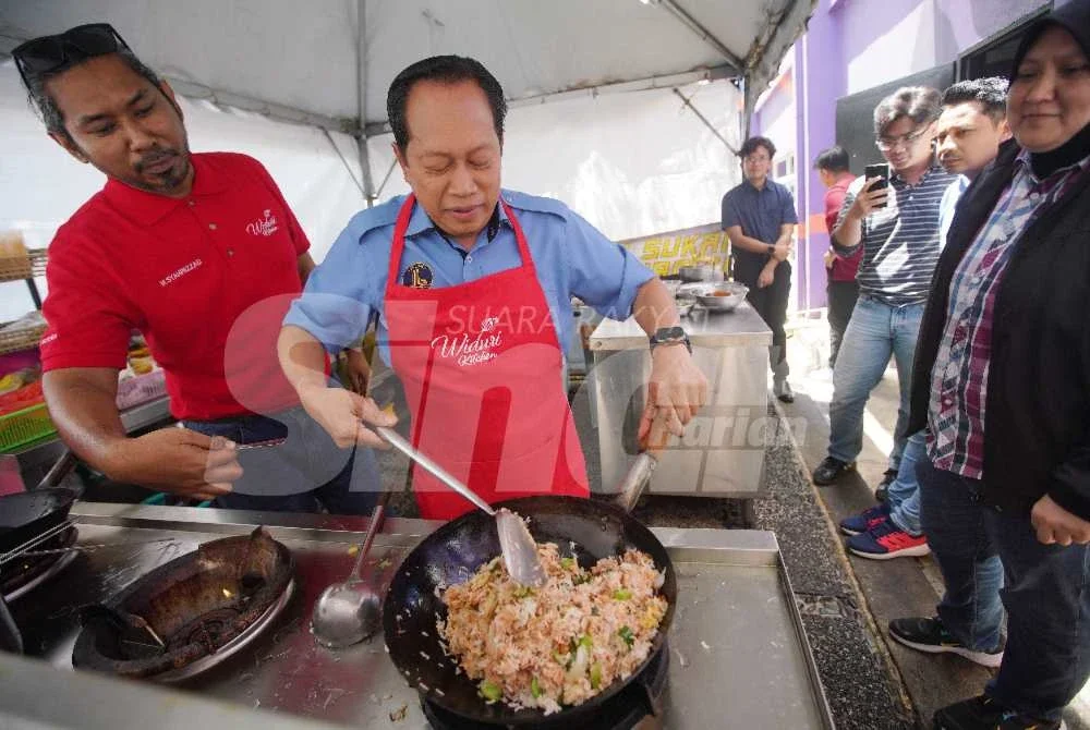 Ahmad mempamerkan kemahiran memasak nasi goreng petai yang beliau namakan Nasi Goreng Ahmad Maslan di kafe Karangkraf semasa sesi kunjungannya pada Khamis. Foto ROSLI TALIB
