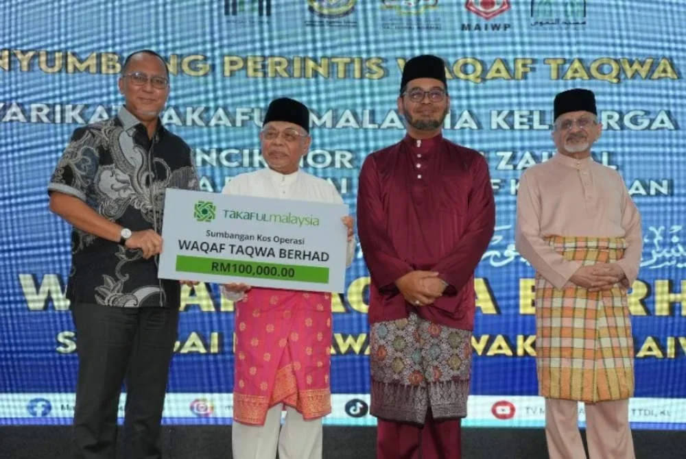 MOHD FADZLI (tengah) menerima replika cek sumbangan Takaful Malaysia untuk operasi Waqaf Taqwa Berhad disaksikan Dr Zulkifli (dua dari kanan) di TTDI, Kuala Lumpur baru-baru ini.