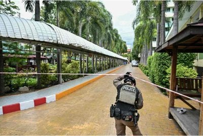 Seorang anggota polis mengawal lokasi kejadian tembakan di sebuah di wilayah Nonthaburi, utara Bangkok pada Jumaat. FOTO: AFP 