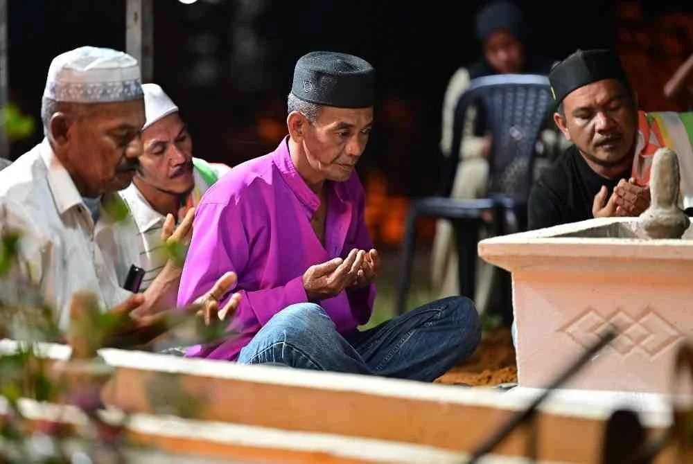 Bapa Konstabel Muhammad Raimi Ismarubee, Ismarubee Ismail, 51 (tengah) mengaminkan doa selepas pengebumian jenazah anaknya yang maut dipercayai akibat terkena renjatan elektrik di Tanah Perkuburan Islam Felda Kerteh 2, malam tadi.