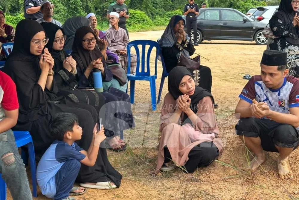Keluarga yang mengaminkan doa semasa upacara pengebumian jenazah.