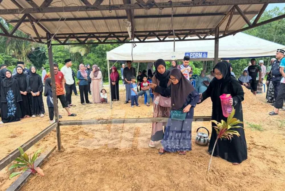 Ibunya (tengah) yang dipegang Nurlella (kanan) untuk mendekati pusara Allahyarham.