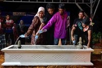 Bapa Konstabel Muhammad Raimi Ismarubee, Ismarubee Ismail, 51 (dua, kanan) bersama isterinya Nor Azila Zakaria, 46 (kiri) menyiram air di pusara anak mereka yang maut dipercayai akibat terkena renjatan elektrik, di Tanah Perkuburan Islam Felda Kerteh 2, malam tadi. Foto Bernama.