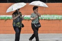 Wanita menggunakan payung bagi melindungi diri daripada panas terik ketika berjalan di sepanjang Jalan Mirae Scientists, Pyongyang. Foto AFP