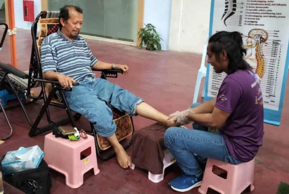 Khairruddin sedang memberikan perkhidmatan mengurut kepada salah seorang pelanggannya.