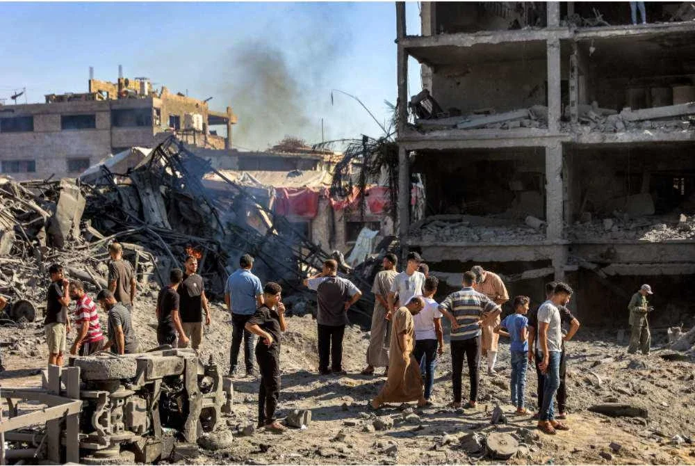 Penduduk berkumpul di lokasi bangunan yang musnah akibat serangan Israel di Bandar Gaza. - AFP
