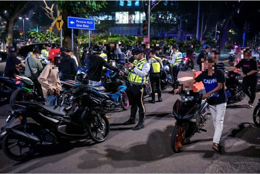 Anggota polis trafik memeriksa penunggang motosikal dan kenderaan mereka menerusi Ops Samseng Jalanan di Jalan Ampang awal pagi Ahad. Foto Bernama