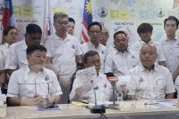 Mohd Shafie (tengah) menunjukkan laporan berita palsu yang mengaitkan Warisan.