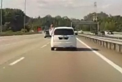 Tular aksi seorang penumpang mengeluarkan sebahagian badannya melalui tingkap belakang Perodua Alza di Lebuhraya Kajang-Seremban.