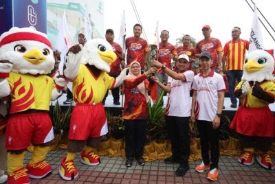 Ani (kiri) menyerahkan obor sempena Larian Obor SUKMA XXII sambil disaksikan Amirudin di Litar Antarabangsa Sepang pada Ahad.