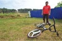 Seorang penduduk menunjukkan basikal milik salah seorang kanak-kanak yangvditemui lemas di ampangan Jalan Murai 2, Taman Scientex.