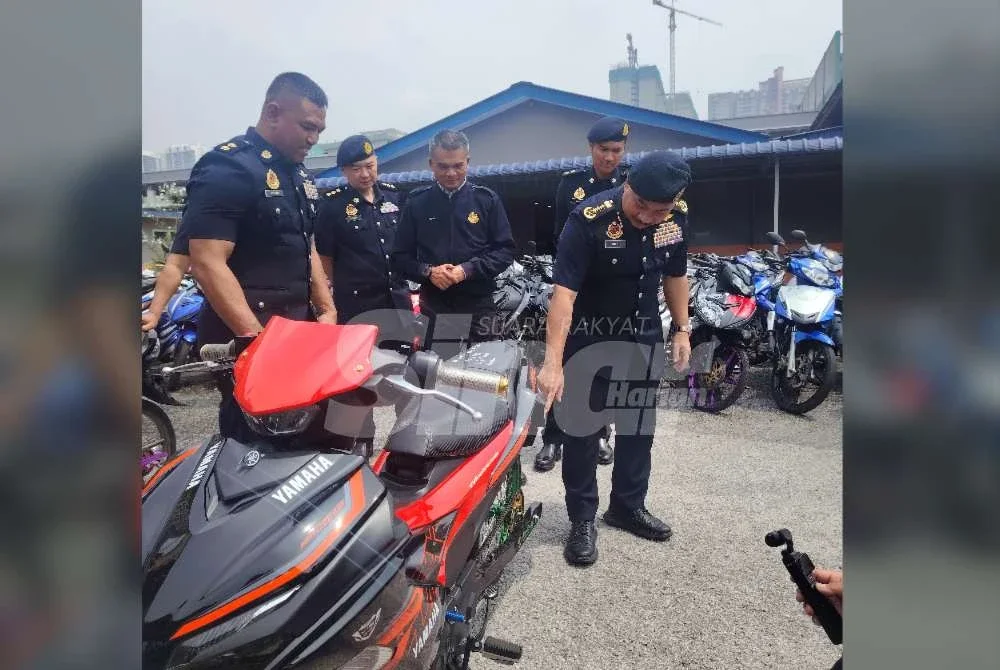 Muhammad Kifli (kanan) menunjukkan keadaan motosikal yang diubah suai ekstrem tanpa brek belakang.