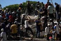 Orang ramai dan anggota penyelamat mencari mangsa yang terselamat di celah runtuhan bangunan yang roboh selepas gempa bumi di Cali, Colombia. - Foto AFP