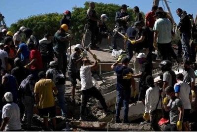Orang ramai dan anggota penyelamat mencari mangsa yang terselamat di celah runtuhan bangunan yang roboh selepas gempa bumi di Cali, Colombia. - Foto AFP