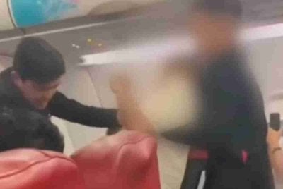 Dua kru kabin lelaki menahan seorang lelaki yang kemudiannya disahkan sebagai seorang leftenan dalam Tentera Diraja Thailand dan mempunyai masalah kesihatan mental. – Foto: Tangkap layar halaman Social Hunter 2022.
