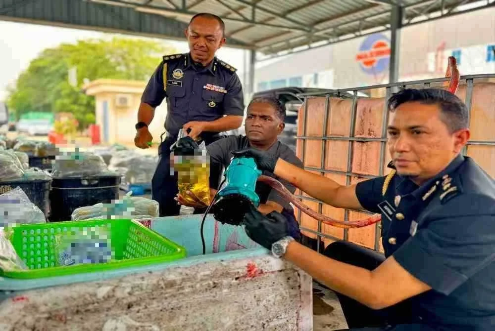 Jegan (tengah) menunjukkan cara sindiket berkenaan memproses minyak masak peket untuk dijadikan minyak masak terpakai yang dijual dengan harga RM3.50 sepeket.