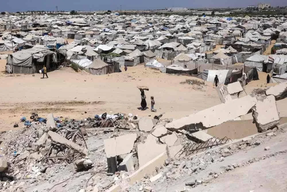Penduduk Palestin yang dipindahkan berjalan melewati runtuhan bangunan dan ratusan penempatan khemah di Khan Yunis, selatan Gaza. Foto AFP