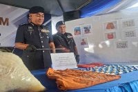 Mohd Alwi (kiri) menunjukkan rampasan dadah bernilai lebih RM18,000 dalam pemeriksaan yang dilakukan polis IPD Manjung di sebuah lokap Balai Polis Lumut, Selasa lalu.