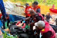 Anggota bomba mengangkat mayat mangsa yang ditemukan lemas di Sungai Kampung Gong Maksom di Kampung Raja, Jertih pada Khamis. - FOTO: Polis