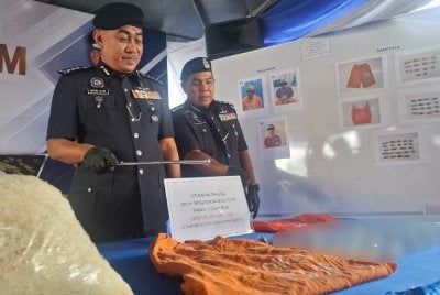 Mohd Alwi (kiri) menunjukkan rampasan dadah bernilai lebih RM18,000 dalam pemeriksaan yang dilakukan polis IPD Manjung di sebuah lokap Balai Polis Lumut, Selasa lalu.