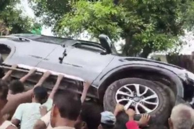 Orang ramai cuba menterbalikkan kenderaan SUV milik doktor berkenaan. Foto kredit The Indian Express