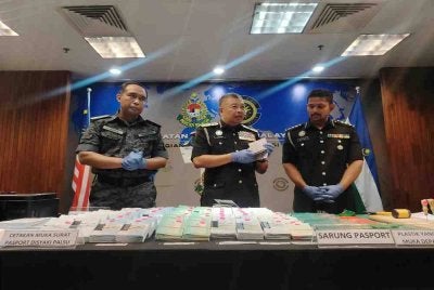 Zakaria (tengah) menunjukkan helaian kertas pasport disyaki palsu yang dirampas susulan tangkapan dua warga Bangladesh di Kuala Lumpur.