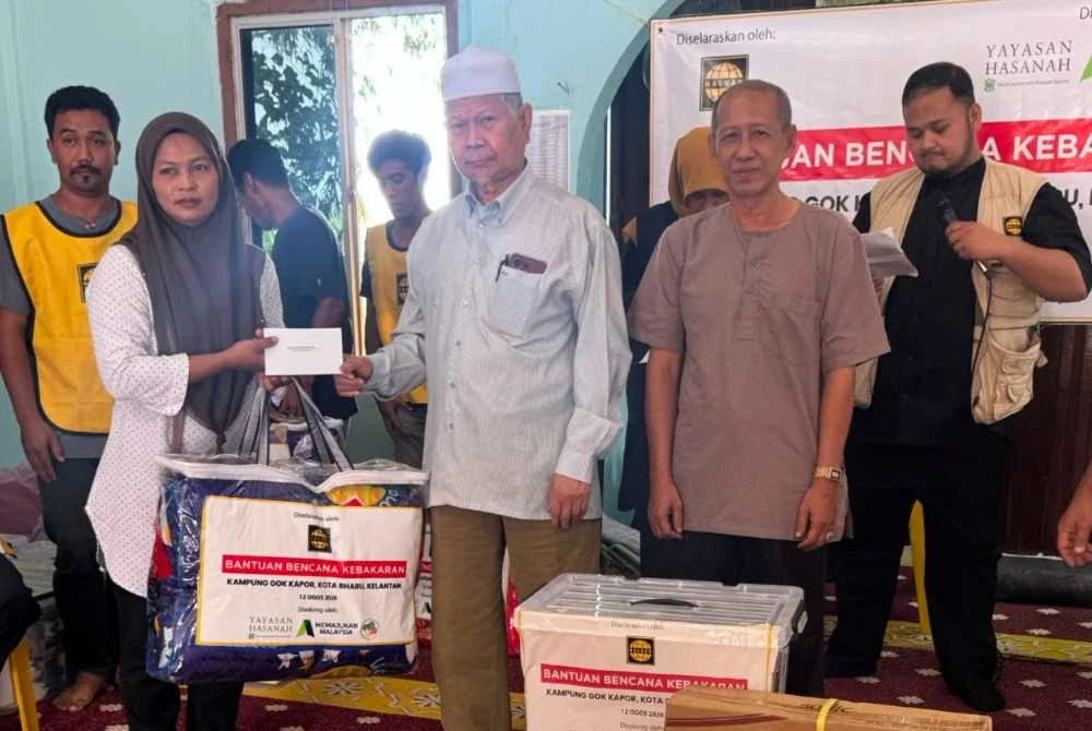 Dr Abdullah Sudin (tiga dari kanan) menyampaikan toto kepada mangsa kebakaran. Foto Haluan