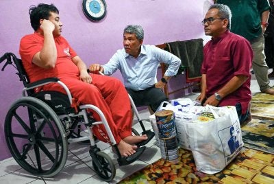 Mohamad (tengah) menyantuni pesakit lumpuh dan saraf Ahmad Khairul Anuar Mohd Zabidi (kiri) pada Program Ziarah Kasih Tokmat di Taman Pinggiran Senawang, Seremban hari ini. Foto: Bernama

