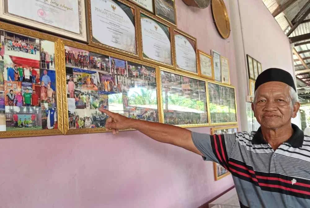 Amar menunjukkan gambar kenangan Kumpulan Tunas Warisan di Kampung Permatang Duku, Pontian.