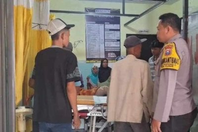 Polis membawa seorang lelaki yang cedera ke Puskesmas Kunir selepas dipercayai diserang isterinya di rumah mereka di Desa Kunir Lor, Lumajang, Jawa Timur. (Foto SuryaMalang.com)