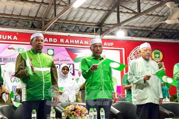 Ahmad (kanan) dan Idris (tengah) mengibarkan bendera Pas ketika nyayian lagu parti itu. FOTO SINAR HARIAN - ADILA SHARINNI WAHID