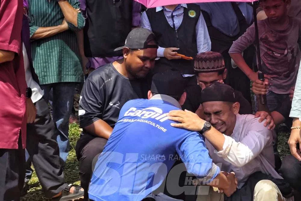 Saifulnizam dipeluk oleh kenalan selepas selesai urusan pengebumian dua beranak di Tanah Perkuburan Islam Kampung Sanggang Temerloh pada Isnin.