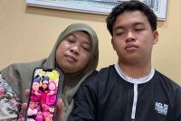 Norasmani dan anaknya menunjukkan gambar kenangan bersama arwah Mohd Khairil.