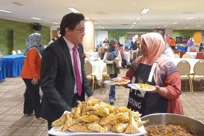 CIK SIAH (kanan) melayan pelanggan yang terdiri daripada kakitangan awam dan swasta.