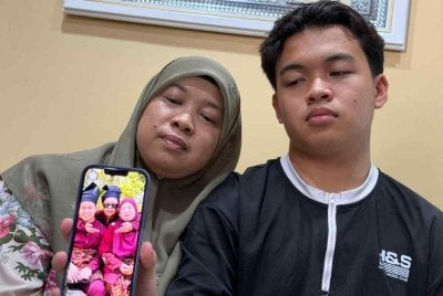 Norasmani dan anaknya menunjukkan gambar kenangan bersama arwah Mohd Khairil.