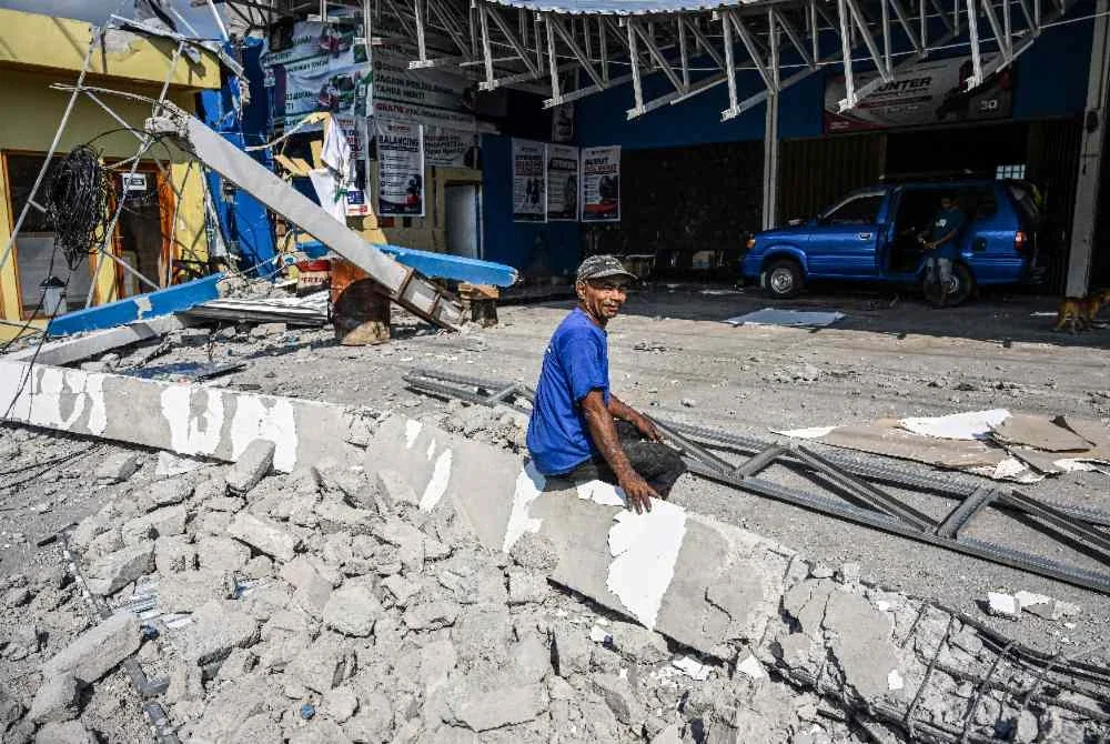 Seorang lelaki duduk di celah runtuhan bangunan yang rosak akibat gempa bumi. Foto AFP