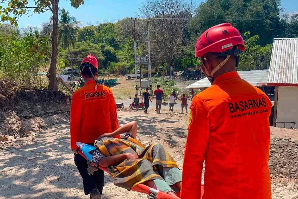 Pasukan penyelamat memindahkan seorang penduduk menggunakan pengusung. Foto AFP