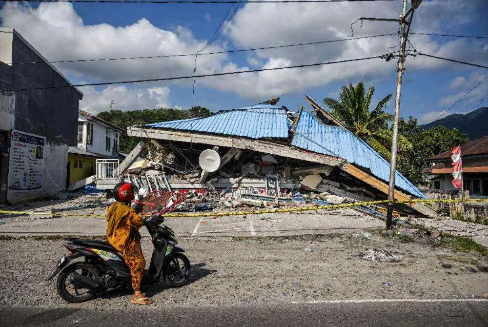 Sebuah motosikal berhenti berhampiran bangunan yang runtuh akibat gempa bumi. Foto AFP