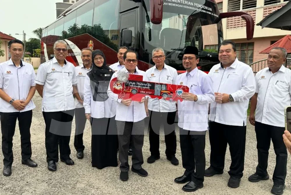 Mohd Azam (empat dari kiri) menyerahkan replika kunci bas kepada pihak sekolah. Foto: ADILA SHARINNI WAHID