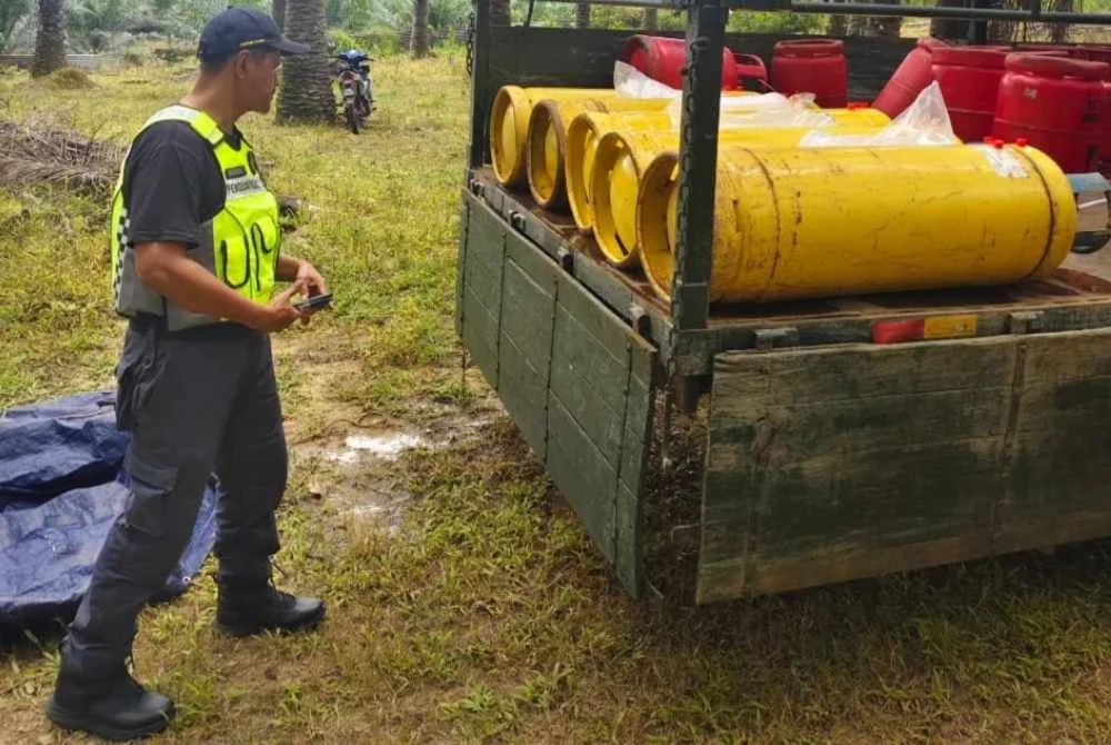 Seorang anggota KPDN sebuah lori membawa tong gas LPG di sebuah ladang kelapa sawit.