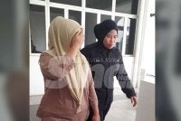 Tertuduh (kiri) dibawa keluar dari Mahkamah Sesyen Kota Tinggi selepas mengaku bersalah menggunakan akauan anaknya yang merupakan OKU untuk transaksi sewa rumah.
