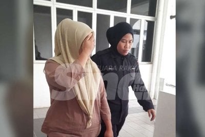 Tertuduh (kiri) dibawa keluar dari Mahkamah Sesyen Kota Tinggi selepas mengaku bersalah menggunakan akauan anaknya yang merupakan OKU untuk transaksi sewa rumah.